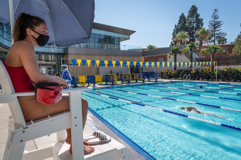 A student lifeguard sits on duty watching other students swim.