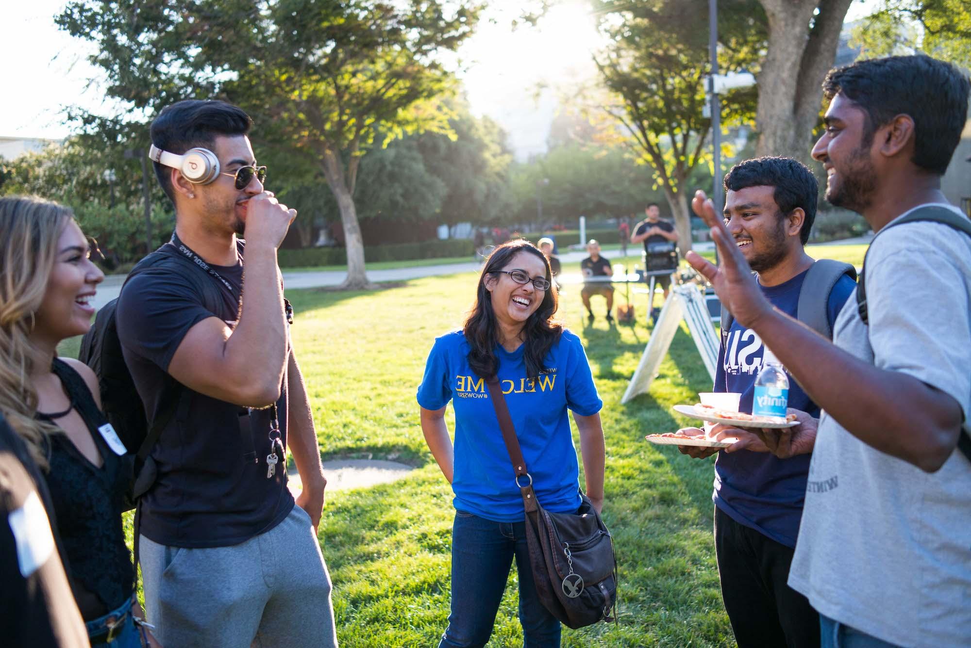 a group of students laughing with eachother in the quad.